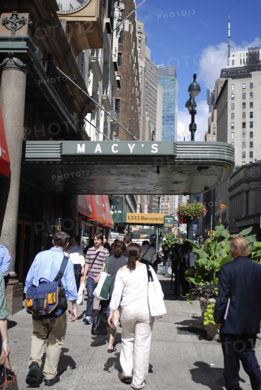 USA, New York, Manhattan, Broadway with people walking along the sidewalk outside the entrance to Macy's department store.