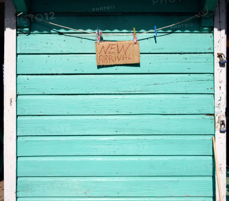 WEST INDIES, Grenada, Carriacou, New Arrival sign on the padlocked turqoise shutter of a shop in Hillsborough.