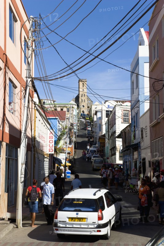 WEST INDIES, Grenada, St George, St Juille Street with overhead power cables busy with traffic and pedestrian shoppers leading to the hurricane damaged and roofless Roman Catholic Cathedral in the capital.