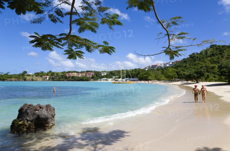 WEST INDIES, Grenada, St George, Gentle waves on BBC Beach in Morne Rouge Bay with tourists in the sea on the beach and aboard their tour catamaran in the aquamarine water.