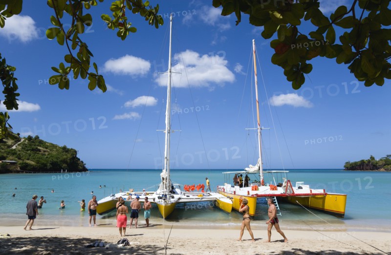 WEST INDIES, Grenada, St George, Tourists from cruise ships on BBC Beach in Morne Rouge Bay in the aquamarine sea on the beach and beside their day trip catamarans at the waters edge.