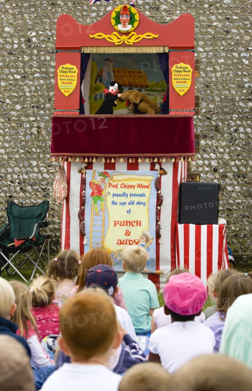 ENGLAND, West Sussex, Findon, Findon village Sheep Fair A group of children sitting on the ground watching a Punch and Judy glove puppet show.