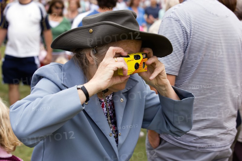 ENGLAND, West Sussex, Findon, Findon village Sheep Fair Elderly lady taking a photograph with a disposable analogue film camera.