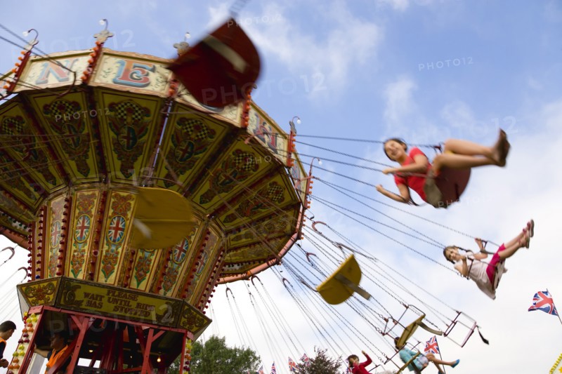 ENGLAND, West Sussex, Findon, Findon village Sheep Fair Children in motion riding on a swing carousel.