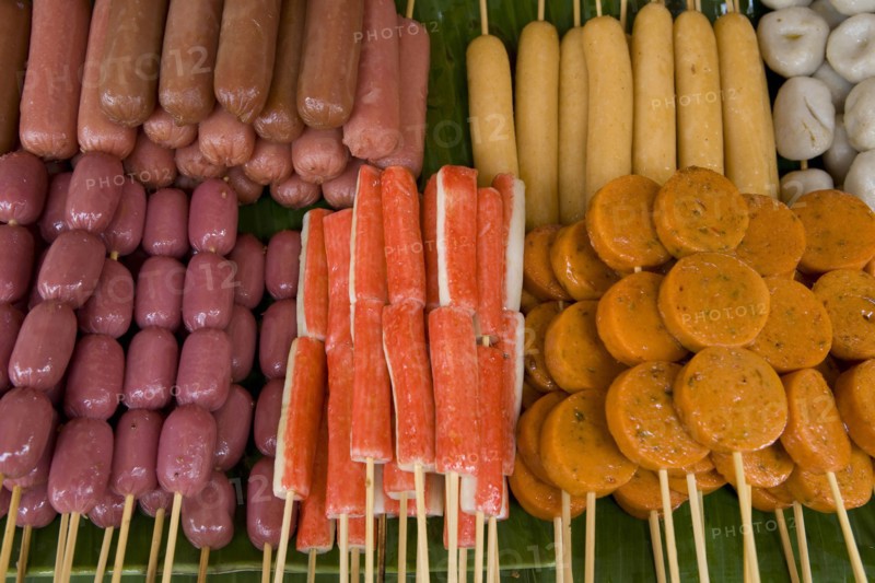 THAILAND, North, Chiang Mai, Close up of a selection of food on wooden skewers in the market.