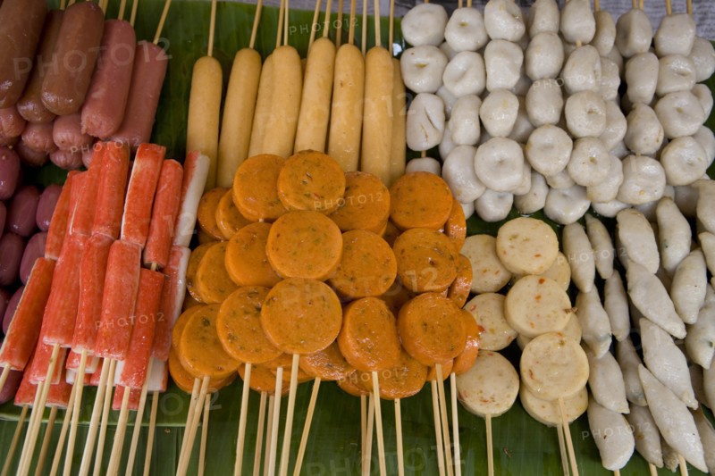 THAILAND, North, Chiang Mai, Close up of a selection of food on wooden skewers in the market.