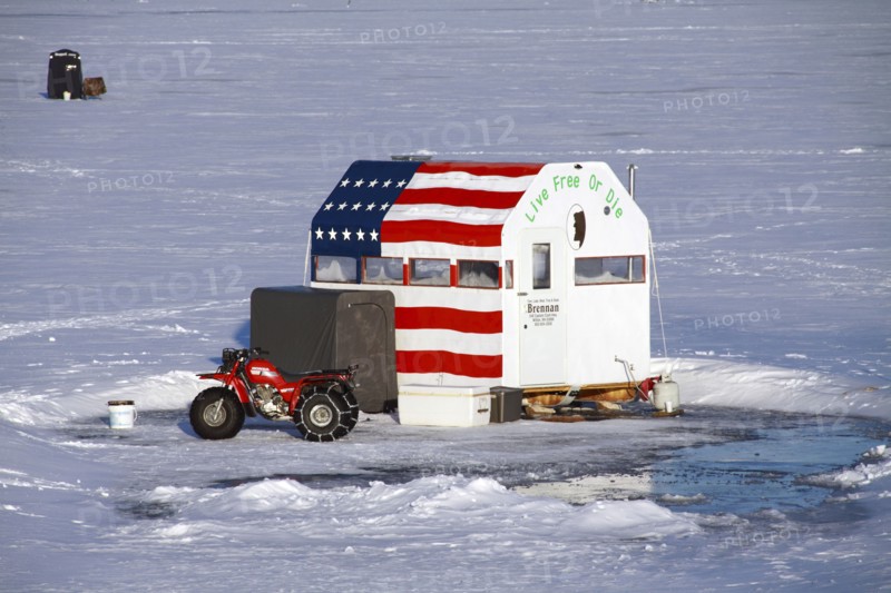USA, New Hampshire, Harrisville, Ice fishermen on Silver Lake. cabin painted with US flag and Live Free or Die message.