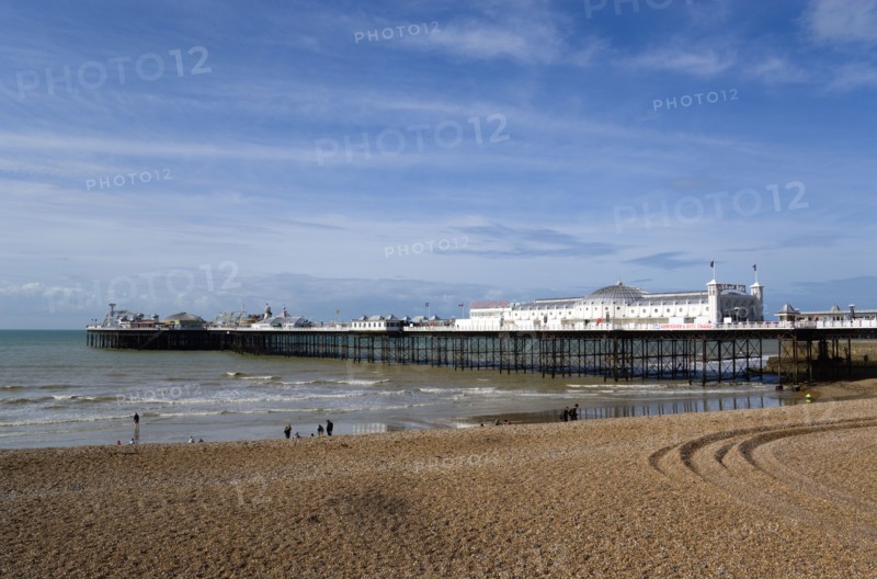 ENGLAND, East Sussex, Brighton, The Pier at low tide with people on the shingle pebble beach.