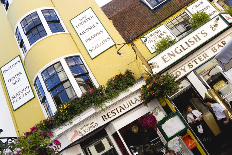 ENGLAND, East Sussex, Brighton, The Lanes Englishs Oyster Bar and Seafood Restaurant exterior with a waitress carrying a cup of coffee and a waiter by the entrance.