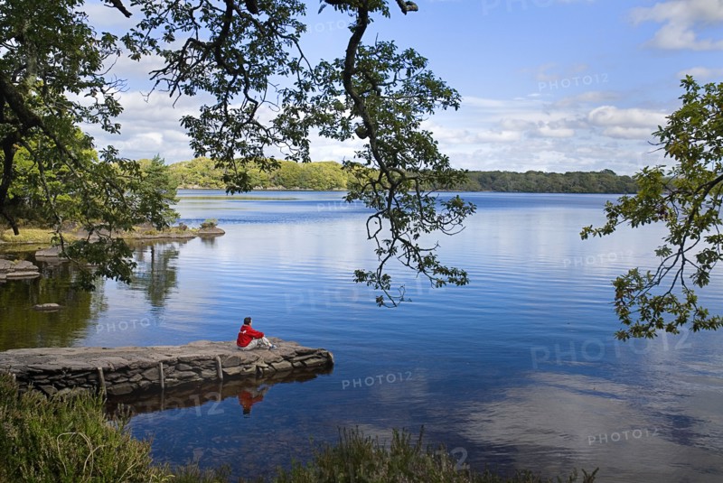 IRELAND, County Kerry, Killarney, Muckross Lake, a figure in red takes in the view.