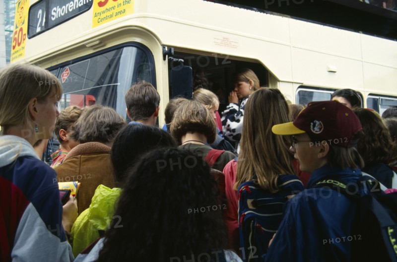 England, East Sussex, Brighton, Young teenage people boarding a crowded bus at a bus stop in the town centre.