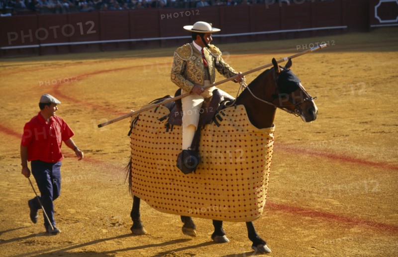 Spain, Andalucia, Seville, Picador with lance riding a padded and blindfolded horse in the bullring at a bullfight in Arenal District.