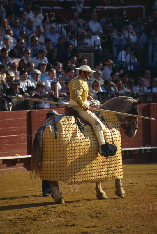 Spain, Andalucia, Seville, Picador with lance riding a padded and blindfolded horse in the bullring at a bullfight in Arenal District.
