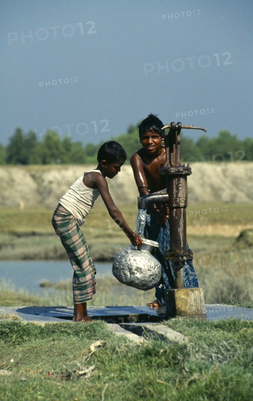 Bangladesh, Hatiya, Two boys drawing water from a UNICEF well into aluminium pitcher.