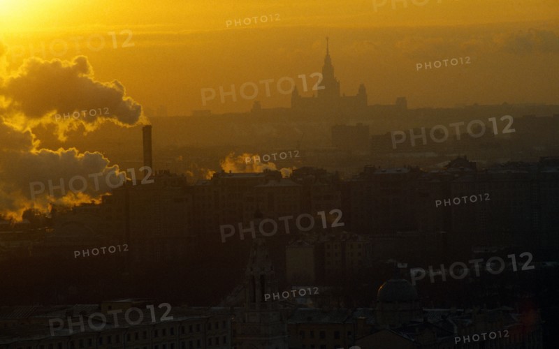Russia, Moscow, Thick smoke from industrial chimneys hanging over the city at sunset.