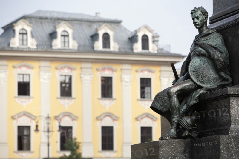 Poland, Krakow, Detail of male figure on monument to the polish romantic poet Adam Mickiewicz by Teodor Rygier in 1898 in the Rynek Glowny market square with pastel coloured building in the background.