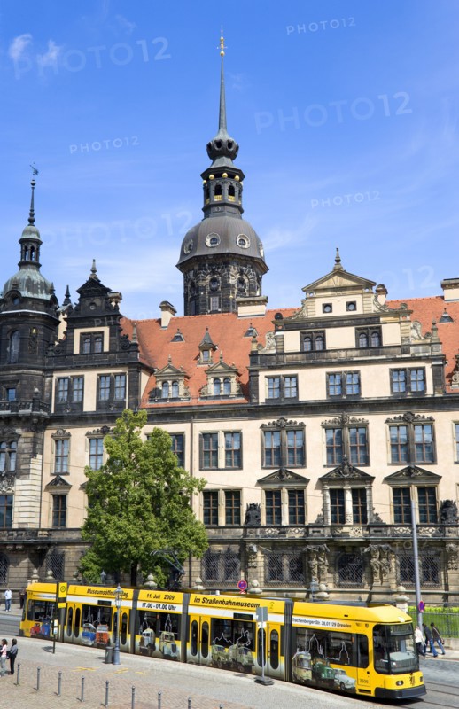 GERMANY, Saxony, Dresden, A yellow tram in the road in front of the Residenzschloss with people walking on sidewalk pavement.