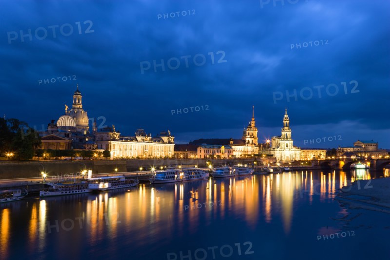 GERMANY, Saxony, Dresden, The city skyline at night with cruise boats moored on the River Elbe in front of the illuminated embankment buildings on the Bruhl Terrace of the Art Academy, the restored Baroque Frauenkirche Dome, the Residenzschloss, the Cathedral of Saint Trinitatis, and the Opera House.