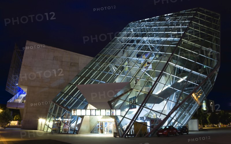 GERMANY, Saxony, Dresden, The angular structure in glass and steel of the 1999 Ufa Palast cinema designed by Austrian architecture firm Coop Himmelblau illuminated at night.
