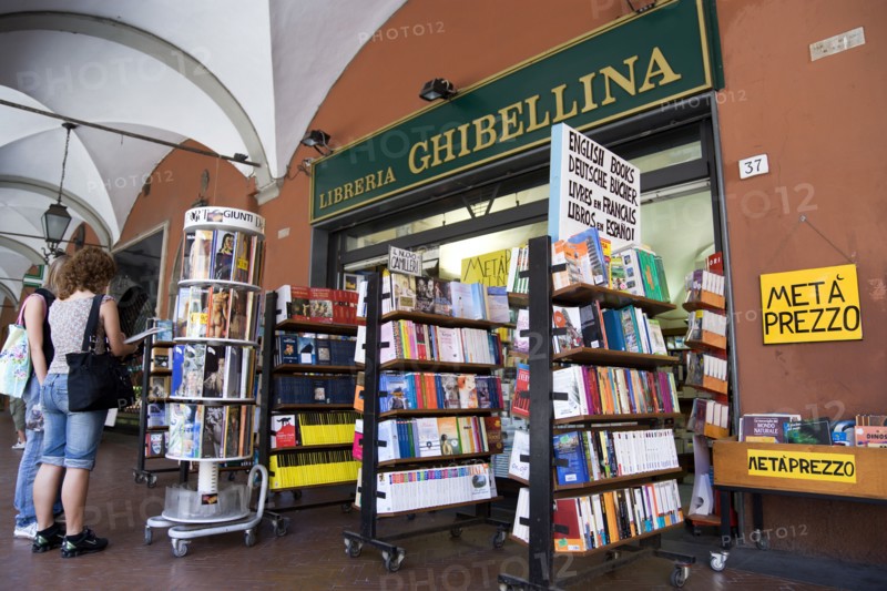 ITALY, Tuscany, Pisa, Two women looking at books ina display outside a bookshop underneath an arched walkway.
