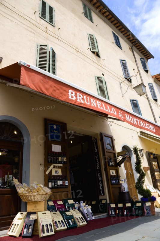 ITALY, Tuscany, Montalcino, Val D'Orcia Brunello di Montalcino Enoteca or wine shop with dispaly of boxed wines on the pavement around its entrance beneath a sunshade.