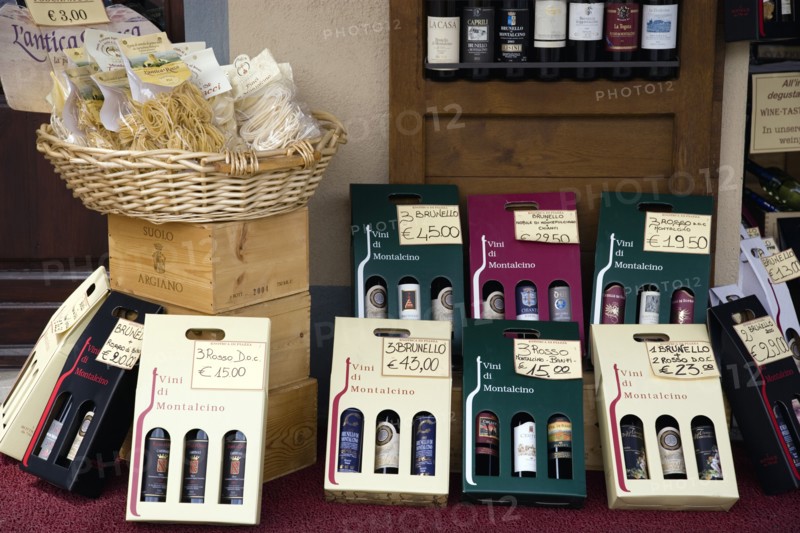 ITALY, Tuscany, Montalcino, Val D'Orcia Brunello di Montalcino Enoteca or wine shop with dispaly of boxed wines and pastas on the pavement around its entrance with prices in Euros.