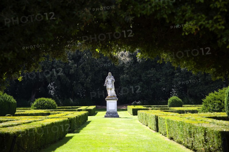 ITALY, Tuscany, San Quirico D'Orcia, The 16th Century Horti Leonini formal gardens by Diomede Leoni seen through an archway of greenery with the 1688 statue of Cosimo III de Medici.
