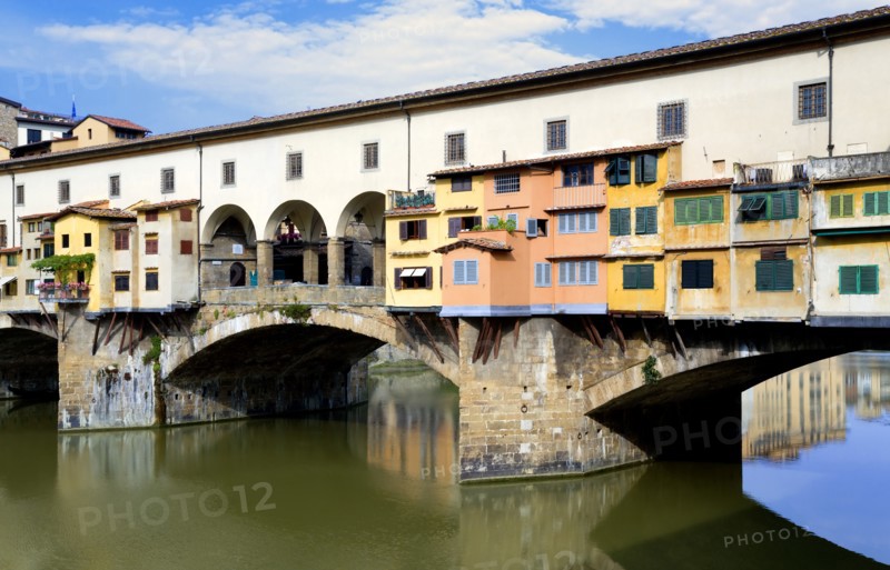 ITALY Tuscany Florence Ponte Vecchio medieval bridge across River Arno with view of merchant's shops that line bridge and hang over the water below.