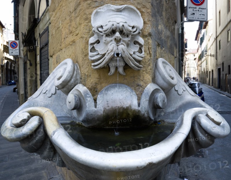 ITALY, Tuscany, Florence, Oltrarno District Drinking water fountain with gargoyle on corner building in Piazza de'Frescobaldi designed by Buontalenti in the 16th Century with narrow streets on either side of it.