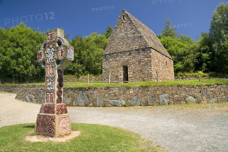 IRELAND, County Wexford, Irish National Heritage Park, Reconstruction of a typical monastic oratory with replica of a celtic cross in front.