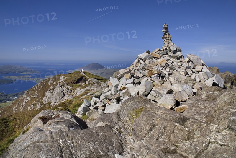 IRELAND, County Galway, Connemara, Diamond Hill, two hikers approach the stone pile at the summit.