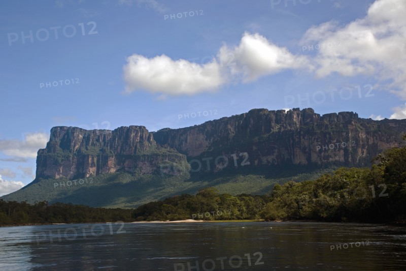VENEZUELA, Bolivar State, Canaima National Park, A big Tepui mountain by the coast of a river shoot on a bright day with blue sky and white clouds