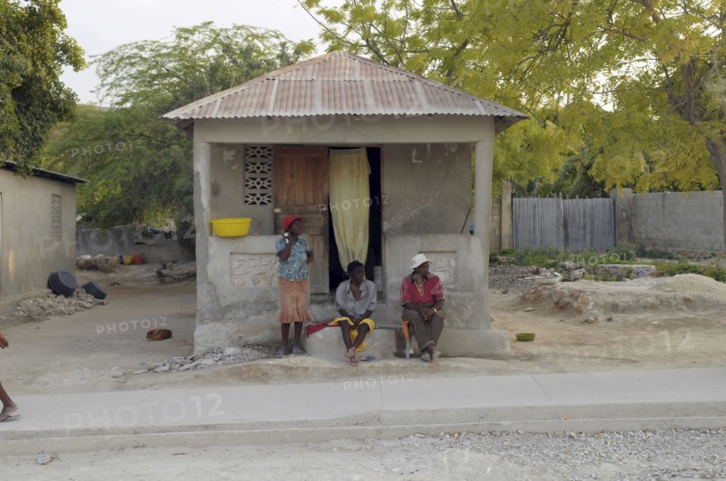 Haiti, Isla de Laganave, local people sat outside hime with tin roof.