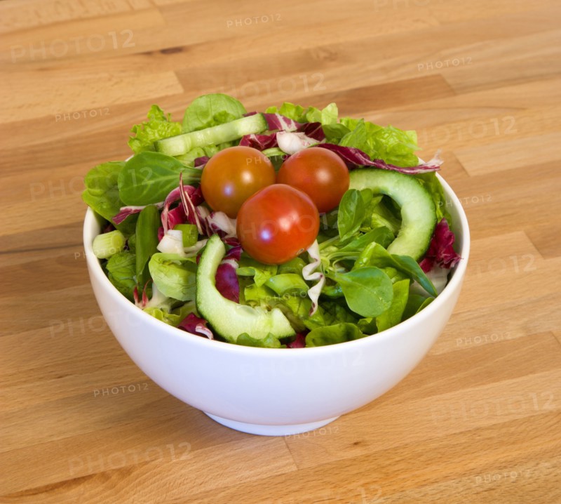Food, Vegetables, Salad, White bowl of green leaf salad with tomatoes and cucumber on a wooden table top.