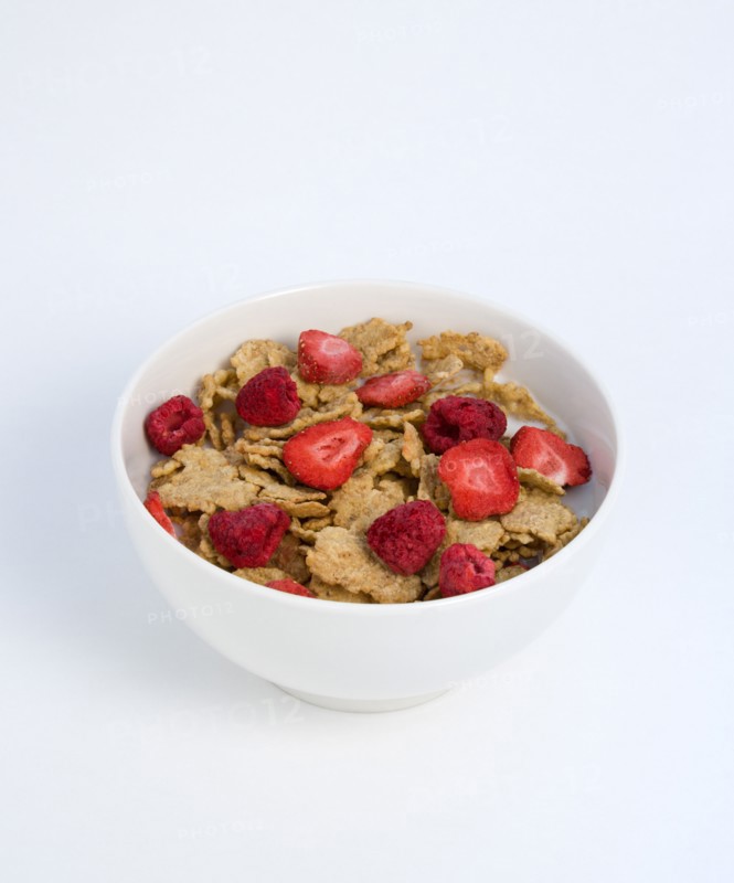 Food, Meals, Cereals, White breakfast bowl of bran flake cereal with freeze dried fruits of strawberries and raspberries in milk on a white background.
