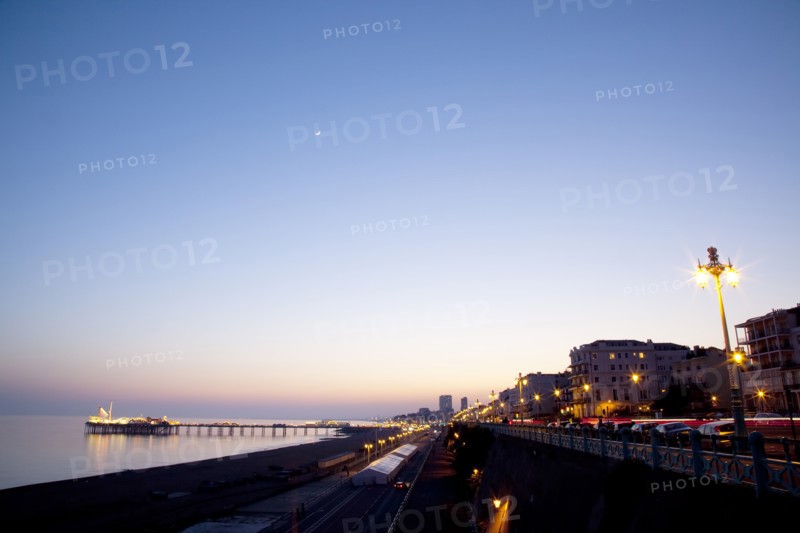 England, East Sussex, Brighton, Kemptown, view over Madeira Drive from Marine Parade with the pier illuminated at sunset. Skies clear due to no fly zone over uk because of Icelandic volcanic dust fears.
