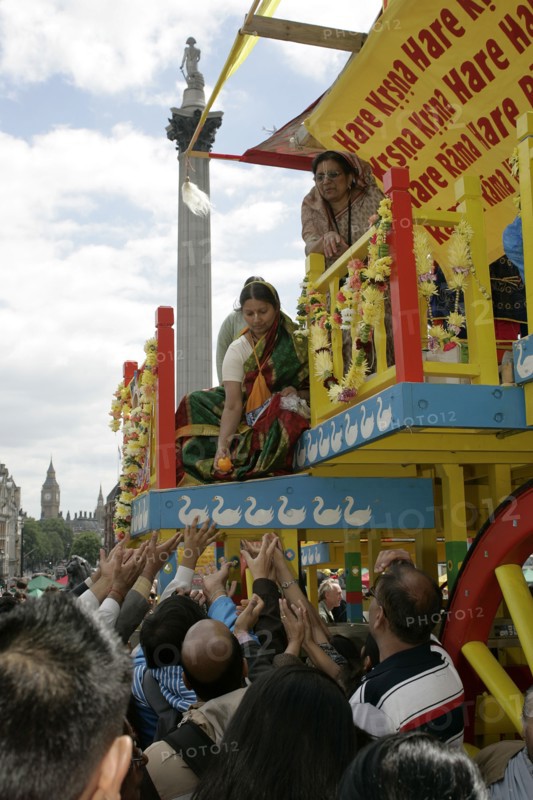 Religion, Hindu, Worship, London Rathayatra celebrations in Trafalgar Square. People handing out offerings during festival. Nelsons Column behind.