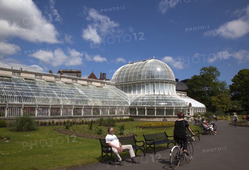 Ireland, Northern, Belfast, Botanic Gardens with people sat on benches outside the Palm House next to Queens University both designe by architect Charles Lanyon.