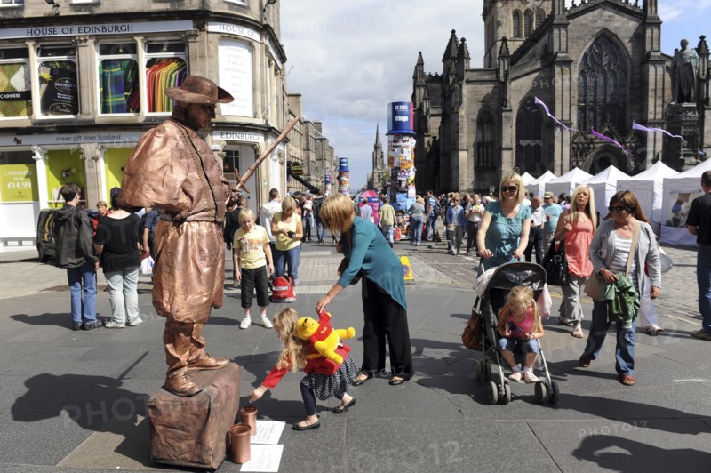 Scotland, Lothian, Edinburgh Fringe Festival of the Arts 2010, Street performers and crowds on the Royal Mile, mime performer with child putting money in a jar.