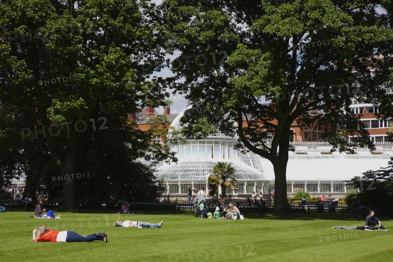 Ireland, Northern, Belfast, Botanic Gardens with people sat on benches outside the Palm House next to Queens University both designe by architect Charles Lanyon.