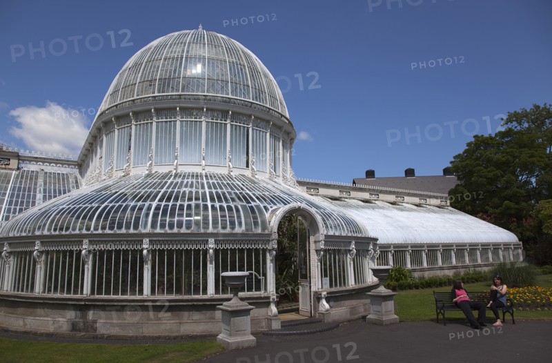 Ireland, Northern, Belfast, Botanic Gardens with people sat on benches outside the Palm House next to Queens University both designe by architect Charles Lanyon.