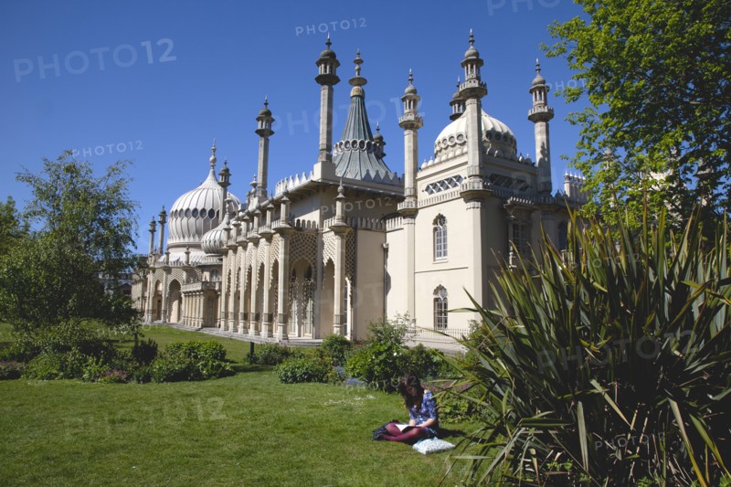 England, East Sussex, Brighton, The Royal Pavilion, 19th century retreat for the then Prince Regent, Designed by John Nash in a Indo Sarascenic style, girl reading in the foreground.