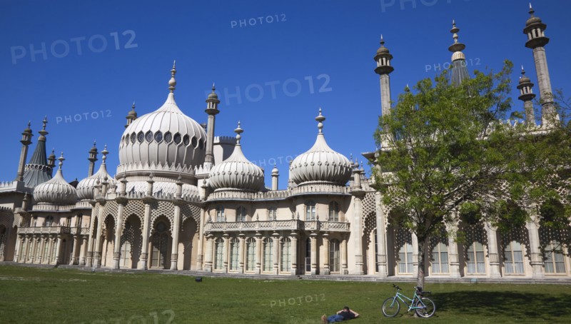 England, East Sussex, Brighton, The Royal Pavilion, 19th century retreat for the then Prince Regent, Designed by John Nash in a Indo Sarascenic style, with cyclist relaxing in the gardens.