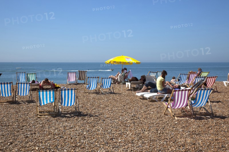 England, East Sussex, Brighton, Deck chairs and sunbathers on the pebble beach.