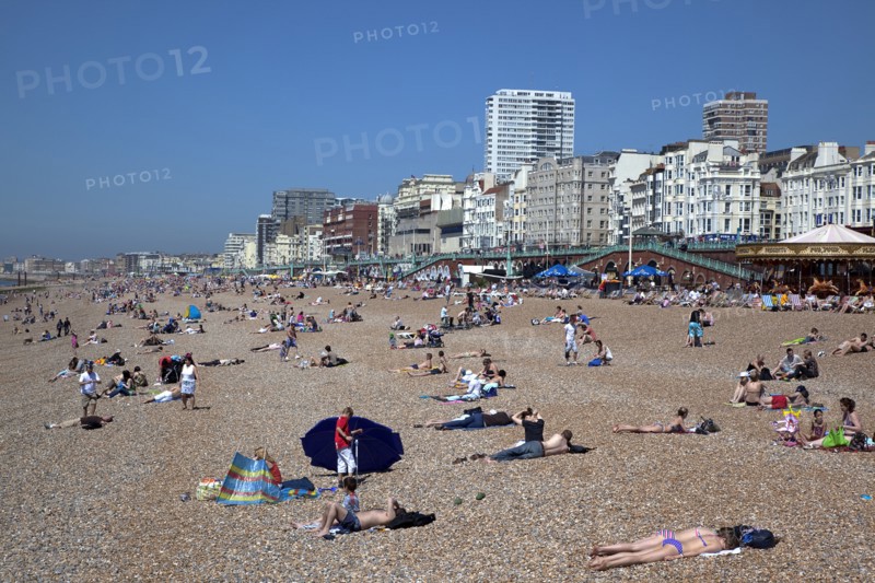 England, East Sussex, Brighton, people sunbathing on the pebble beach.