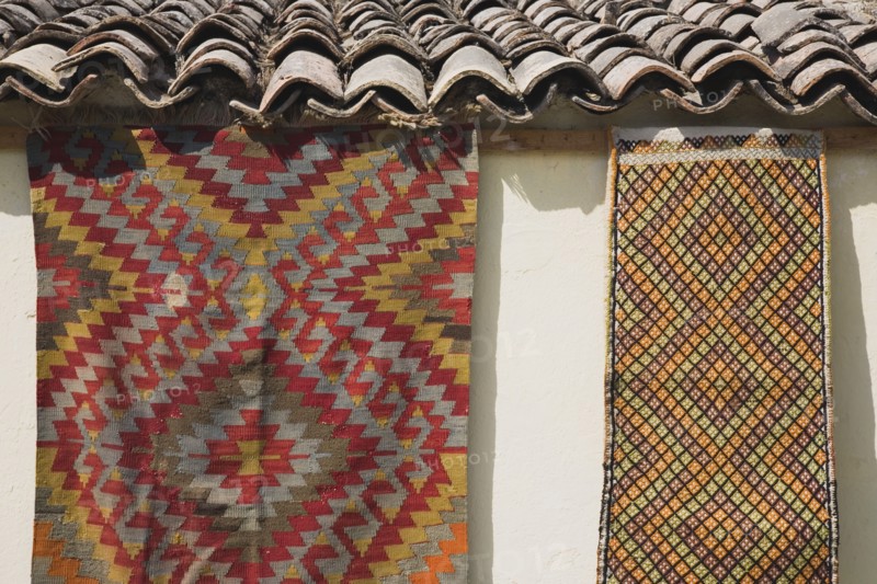 Selcuk, Izmir Province, Turkey. Kilims hanging up to dry in sunshine on walls of village house. Turkey Turkish Eurasia Eurasian Europe Asia Turkiye Izmir Province Selcuk Kilim Kilims Rug Rugs Carpet Carpets Hanging Roof Tiles Slates Destination Destinations European Middle East South Eastern Europe Western Asia