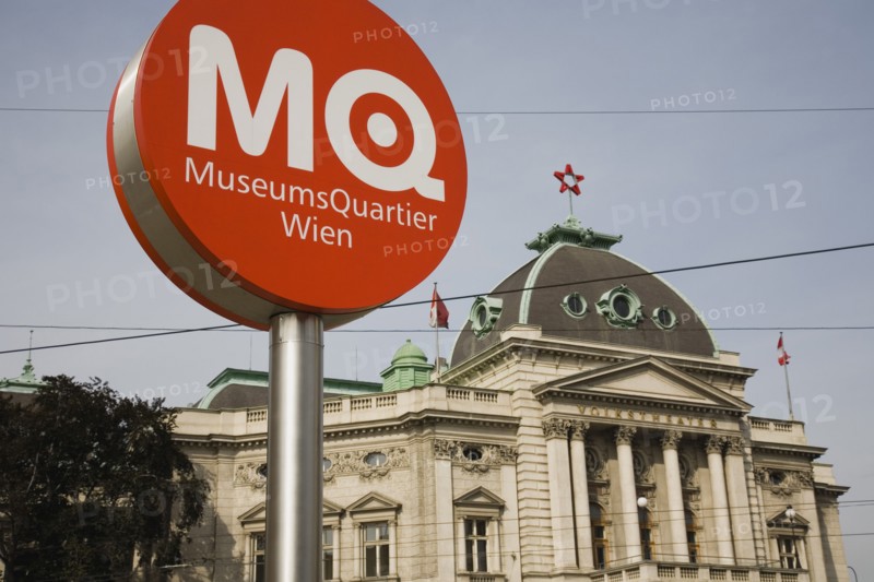 Vienna, Austria. Neubau District. Circular information sign with MQ in white on orange to indicate the Museums Quartier or Museums Quarter outside The Volkstheater. Austria Austrian Republic Vienna Viennese Wien Europe European City Capital Neubau District Sign Signs Information MQ Museums Quarter Vokstheater Architecture Building Exterior Facade Color Destination Destinations Osterreich Signs Display Posted Signage Viena Western Europe