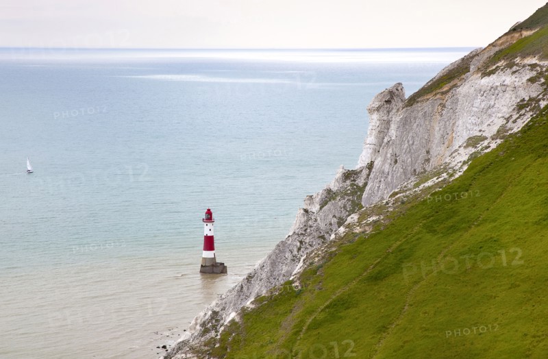 Eastbourne, East Sussex, England. Beachy Head view of the lighthouse at the base of the chalk cliffs. England English UK United Kingdom GB Great Britain Birtish East Sussex County Eastbourne Beachy Head Sea Coast Chalk Cliff Cliffs White Lighthouse Light House Boat Ship Transport Warning