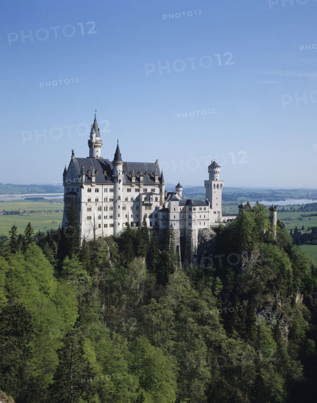 Fussen, Bavaria, Germany. Neuschwanstein Castle of King Ludwig on rocky hill. Germany German Euro Europe European Castle Hill View Fort History Kasteel Neush Beieren Schwanstein Duitsland Neuschwanstein King Ludwig Forest Trees perched Rock Outcrop Hill Bayern Blue Castillo Castello Color Destination Destinations Deutschland Gray History Historic Western Europe