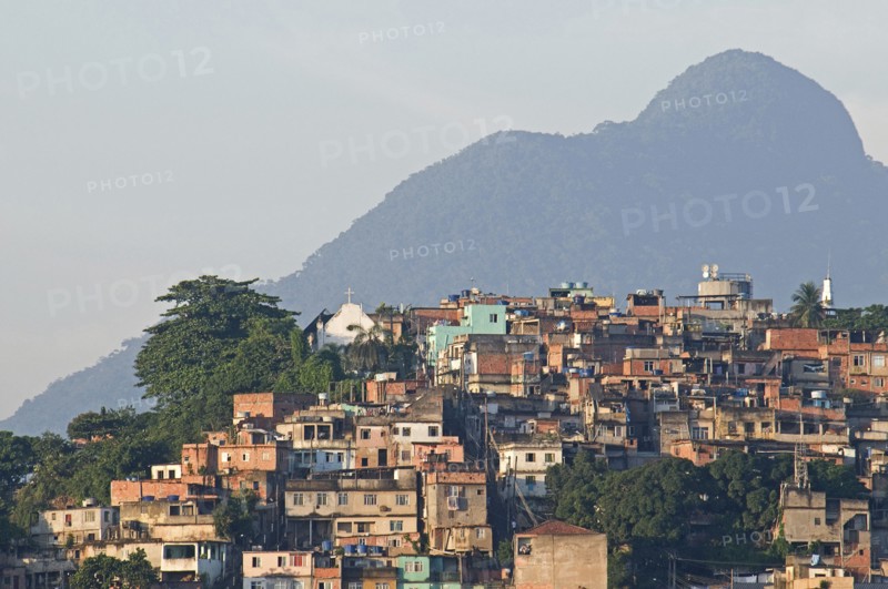 Rio de Janeiro, Brazil. Favela or slum above Saude neighbourhood brick houses trees Church and mountain in the background. Brazil Brasil Brazilian Brasilian South America Latin Latino American City Urban Architecture Houses Housing Homes Suade Neighborhood Neighbourhood Favela Favelas Slum Slums Church Rio de Janeiro Church Destination Destinations Latin America Shanty South America Southern